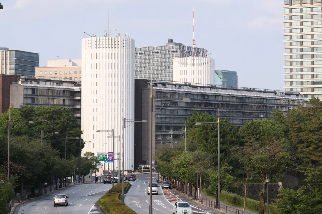 道路の先に並ぶ、パレスサイドビルの二つの白い円筒コア