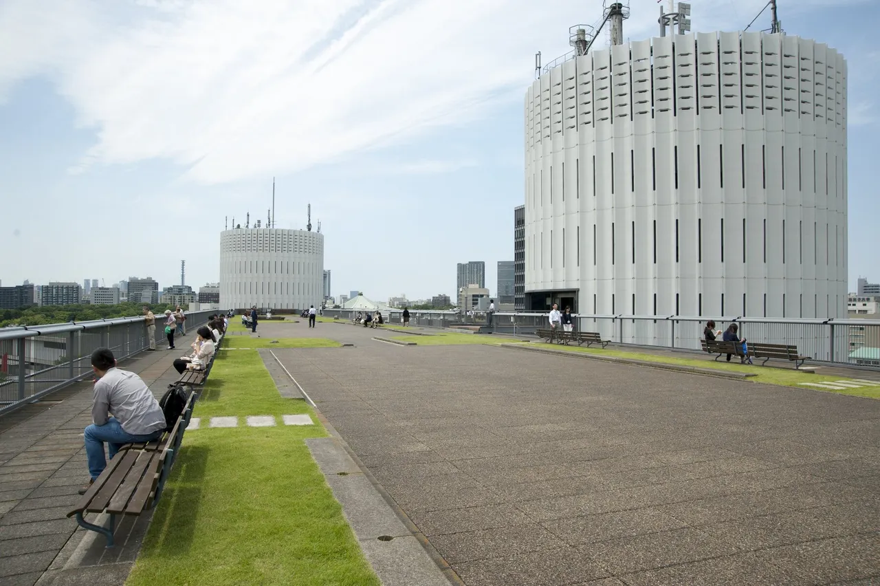 二つの白い円筒コアと、働く人が憩う屋上庭園